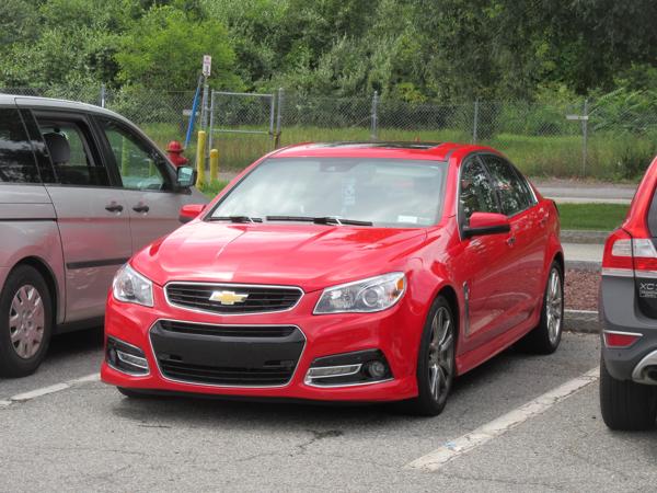 A red car photographed from the front, with no license plate on the car.